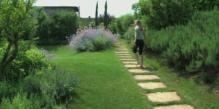 金发女人走在美丽的托斯卡纳花圃里