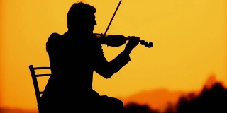 一个小提琴家在日落时的剪影