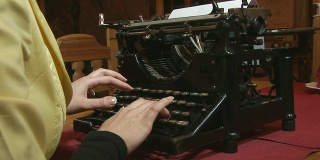 一个女人在给一台很旧的打字机写信