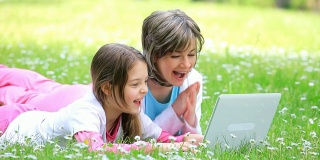妈妈和女儿在电脑上打字，在公园里大笑。