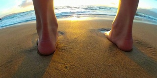 海浪冲刷着海滩上年轻女孩的脚