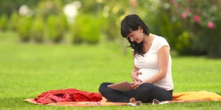孕妇在户外使用平板电脑