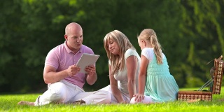 HD DOLLY:年轻的家庭在公园使用数字平板电脑