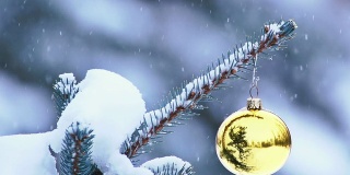雪花轻轻地飘落在挂在树上的圣诞装饰品上