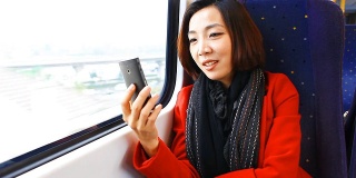 一个年轻的亚洲女人在火车上和朋友聊天。