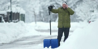 一个男人在铲雪的时候打电话