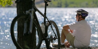 骑自行车的人坐在风景如画的湖边