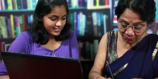 愉快的印度老年妇女和少女使用笔记本电脑