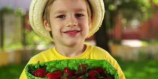 小男孩拿着一个装满草莓的篮子