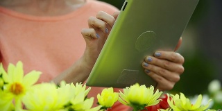 白人妇女在花房用平板电脑买花