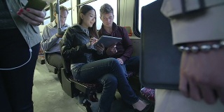 公交车上的乘客在玩平板电脑