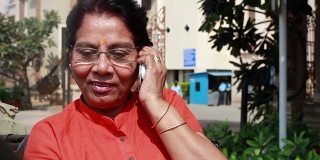 愉快的印度老妇人在户外打电话