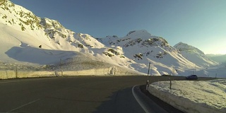 日落时分，车辆POV在雪山路上行驶