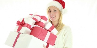 快乐的年轻女子戴着圣诞帽，拿着礼物