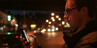 男人在用智能手机，晚上。