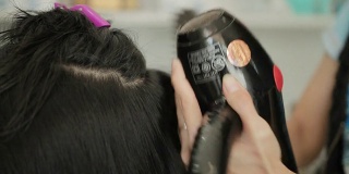 亚洲妇女在美容院理发后正在烘干头发