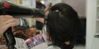 亚洲妇女在美容院理发后正在烘干头发