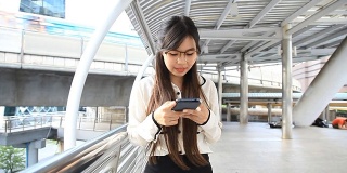 高清STEADYCAM:快乐的女商人通过智能手机行走和发送信息。