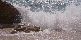 慢动作海浪粉碎在海滩上的岩石