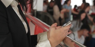 亚洲女商人使用智能手机上网与人群旅行的背景