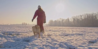 在雪中与小狗一起奔跑的女孩