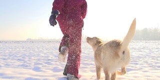 慢动作女孩和她的小狗在雪中奔跑