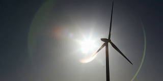 风力涡轮机剪影与太阳和镜头耀斑