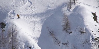 自由式滑雪者从悬崖上跳下，坠入雪崩