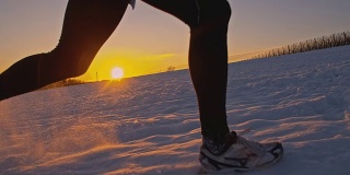 SLO MO慢跑者在夕阳下的雪中跋涉