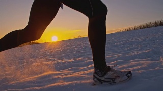 SLO MO慢跑者在夕阳下的雪中跋涉视频素材模板下载