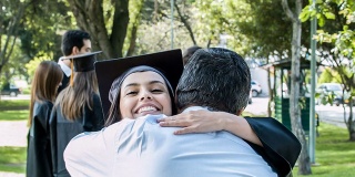 快乐的毕业女子拥抱她骄傲的父亲