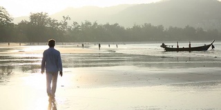 日出时分，一名男子在海滩上用智能手机拍照