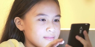 一个年轻的亚洲女孩使用智能手机的特写