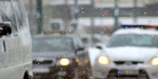 车流在雪中，雪花飘飘，汽车在湿滑的路上行驶，