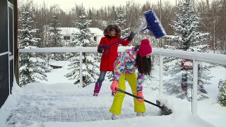 母亲和女儿在铲房子甲板上的雪视频素材模板下载