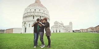 在比萨奇迹oli广场(Piazza dei Miracoli)，朋友们拿着数字平板电脑