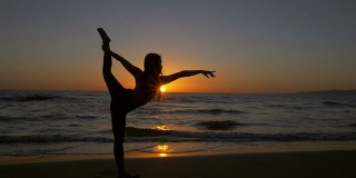 年轻的亚洲女人伸展瑜伽姿势在海滩上日落