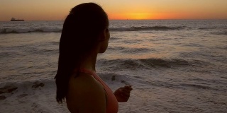 美丽的年轻亚洲女人凝视日落在沙滩上跑步后