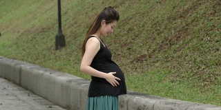 快乐的华裔孕妇在公园享受自然