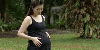快乐的华裔孕妇在公园享受自然