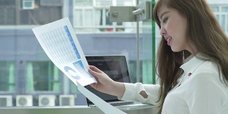 亚洲女商人在办公室走廊使用笔记本电脑和分析文件。