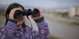 小女孩用双筒望远镜看