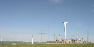 蓝天下旋转风力发电机组和变压器机组，实时运行。