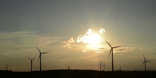 旋转的风力涡轮机，草地，日落时的天空，实时。
