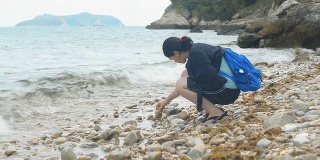 女人在沙滩上玩小石头