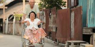 一位老人用轮椅推着她残疾的妻子