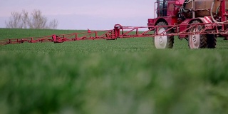 农民用拖拉机给麦田喷洒农药。