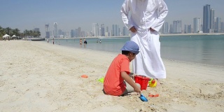 酋长国的爷爷和小男孩在沙滩上玩