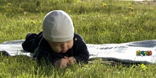 婴儿在毯子上探索草地。