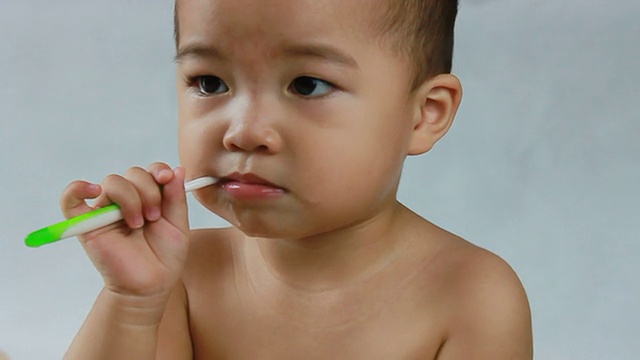 婴儿咀嚼牙刷，盯着左边，特写